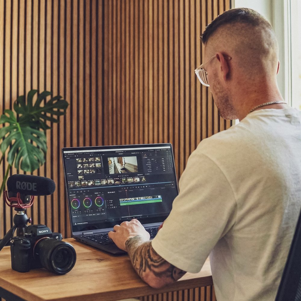 Maik Klemmer beim Videoschnitt am Laptop, daneben Kamera mit Mikrofon