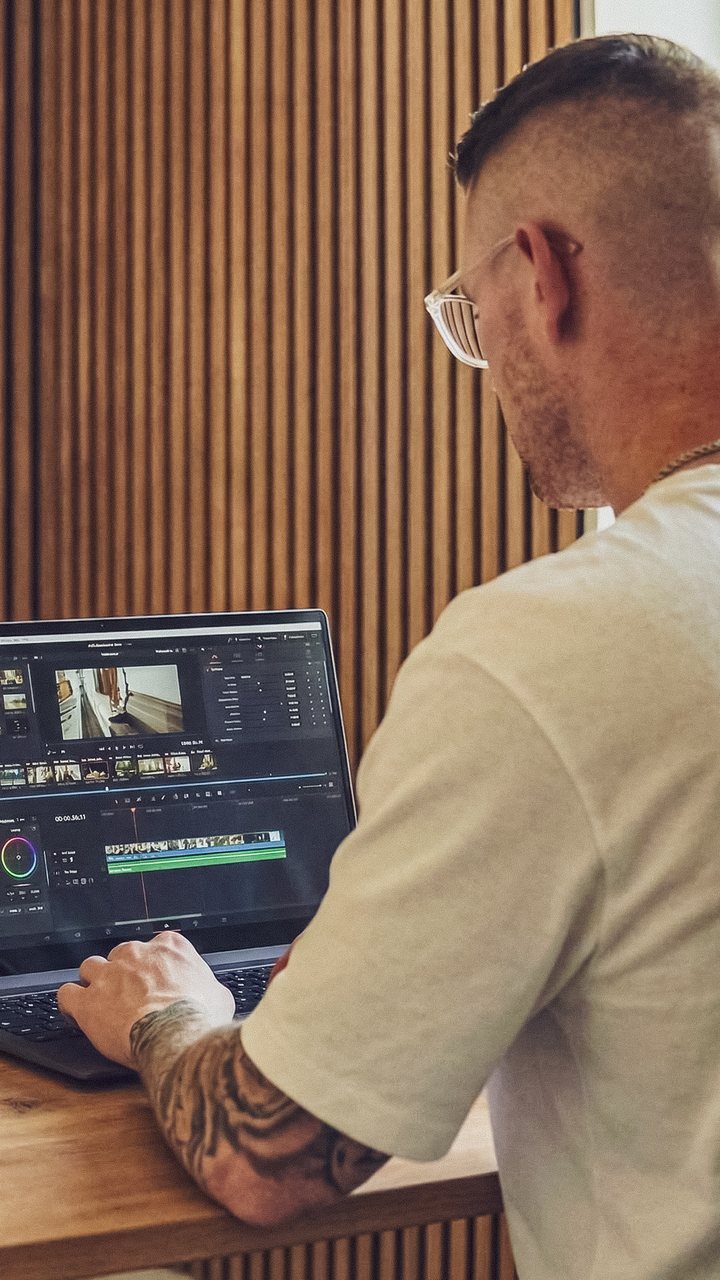 Maik Klemmer beim Videoschnitt am Laptop, Kamera und Mikrofon daneben